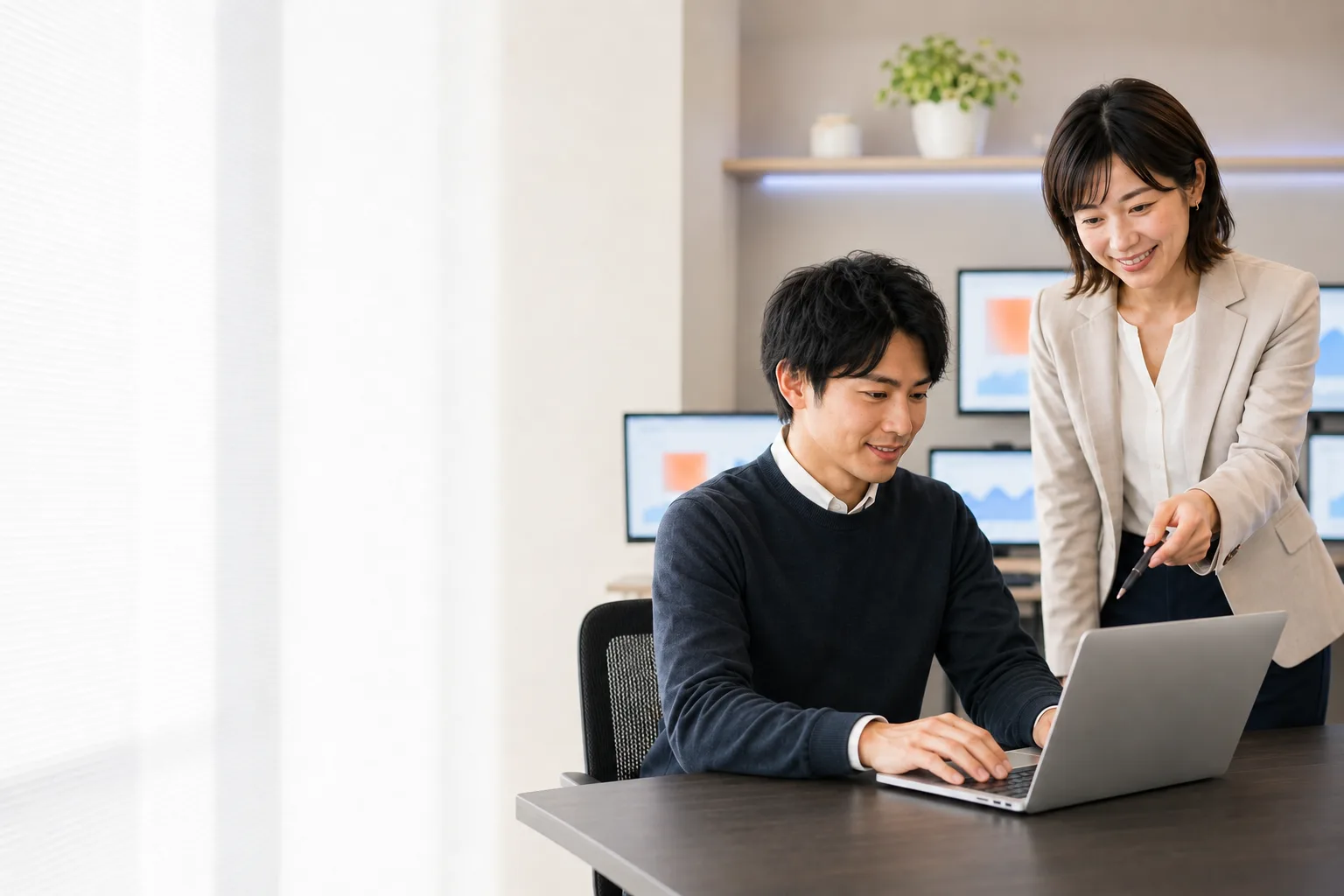 ノートPCの広告成果をペンで指し示しながら確認する2人